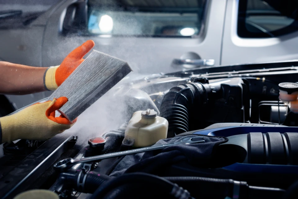 Technicien climatisation en salopette grise et casquette consulte tablette numérique devant unité extérieure pompe à chaleur